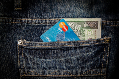 Karta płatnicza i gotówka w kieszeni spodni
