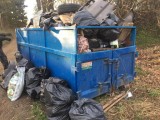 Kontener wypełniony odpadami, obok kilka worków wypełnionych śmieciami