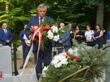 Radny wojewódzki Czesław Łączak składa kwiaty na zbiorowej mogile. W tle uczestnicy uroczystości