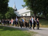 Grupa osób idzie drogą, w tle kościół